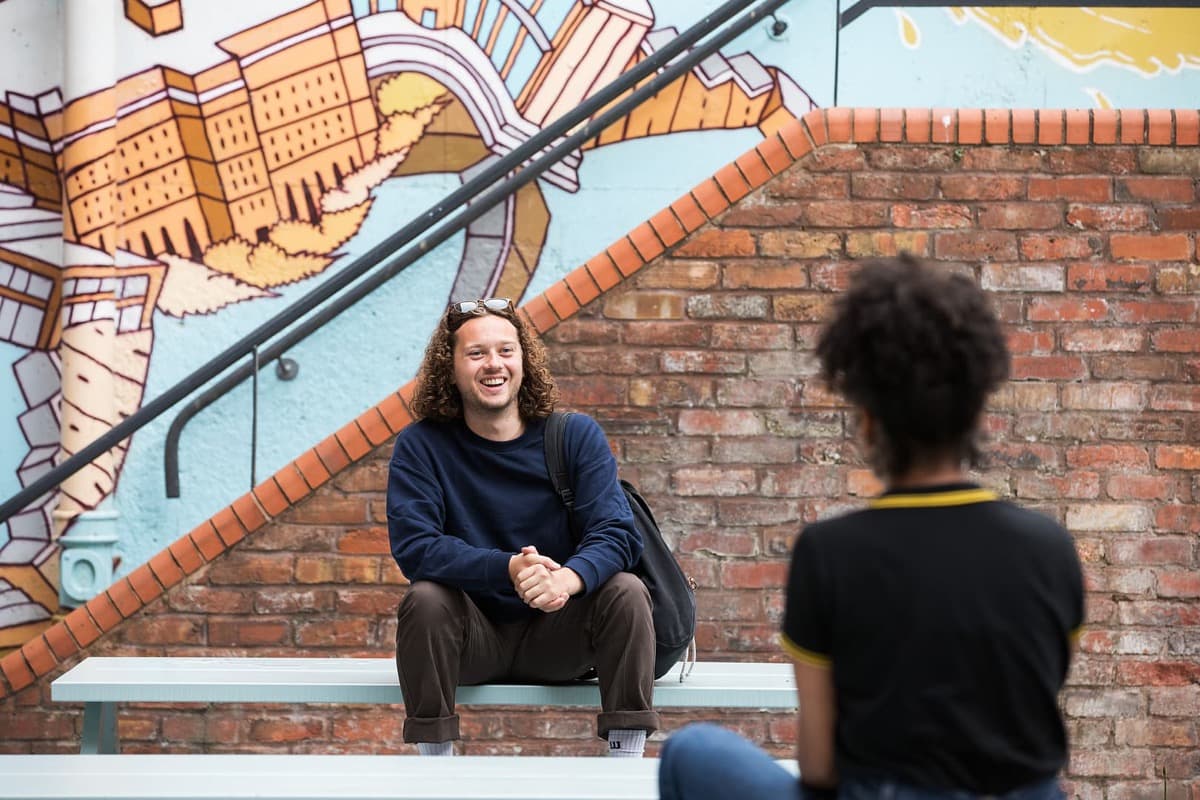 Unite Students member of staff speaking to a person sat on a bench about wellbeing